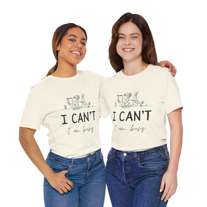 I Can’t, I’m Busy Unisex Jersey Short Sleeve TeeShow off your love for quiet moments with our I Can’t, I’m Busy Unisex Jersey Short Sleeve Tee. Perfect for book lovers and those who cherish their downtime, this tee features a playful illustration of a per