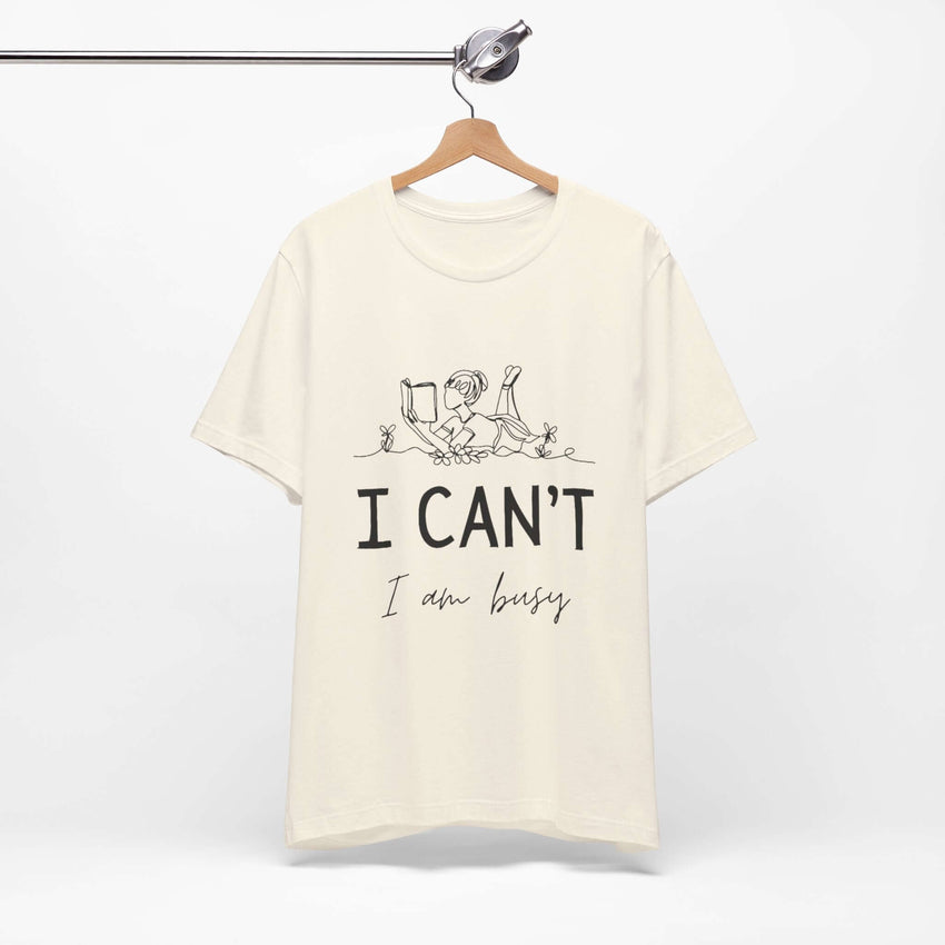 I Can’t, I’m Busy Unisex Jersey Short Sleeve TeeShow off your love for quiet moments with our I Can’t, I’m Busy Unisex Jersey Short Sleeve Tee. Perfect for book lovers and those who cherish their downtime, this tee features a playful illustration of a per