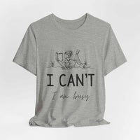 I Can’t, I’m Busy Unisex Jersey Short Sleeve TeeShow off your love for quiet moments with our I Can’t, I’m Busy Unisex Jersey Short Sleeve Tee. Perfect for book lovers and those who cherish their downtime, this tee features a playful illustration of a per