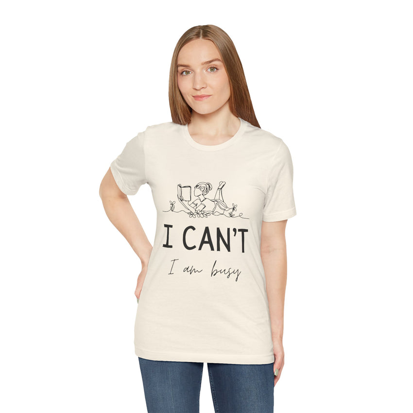 I Can’t, I’m Busy Unisex Jersey Short Sleeve TeeShow off your love for quiet moments with our I Can’t, I’m Busy Unisex Jersey Short Sleeve Tee. Perfect for book lovers and those who cherish their downtime, this tee features a playful illustration of a per