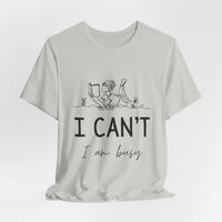 I Can’t, I’m Busy Unisex Jersey Short Sleeve TeeShow off your love for quiet moments with our I Can’t, I’m Busy Unisex Jersey Short Sleeve Tee. Perfect for book lovers and those who cherish their downtime, this tee features a playful illustration of a per