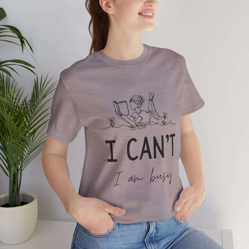 I Can’t, I’m Busy Unisex Jersey Short Sleeve TeeShow off your love for quiet moments with our I Can’t, I’m Busy Unisex Jersey Short Sleeve Tee. Perfect for book lovers and those who cherish their downtime, this tee features a playful illustration of a per