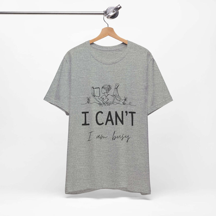 I Can’t, I’m Busy Unisex Jersey Short Sleeve TeeShow off your love for quiet moments with our I Can’t, I’m Busy Unisex Jersey Short Sleeve Tee. Perfect for book lovers and those who cherish their downtime, this tee features a playful illustration of a per