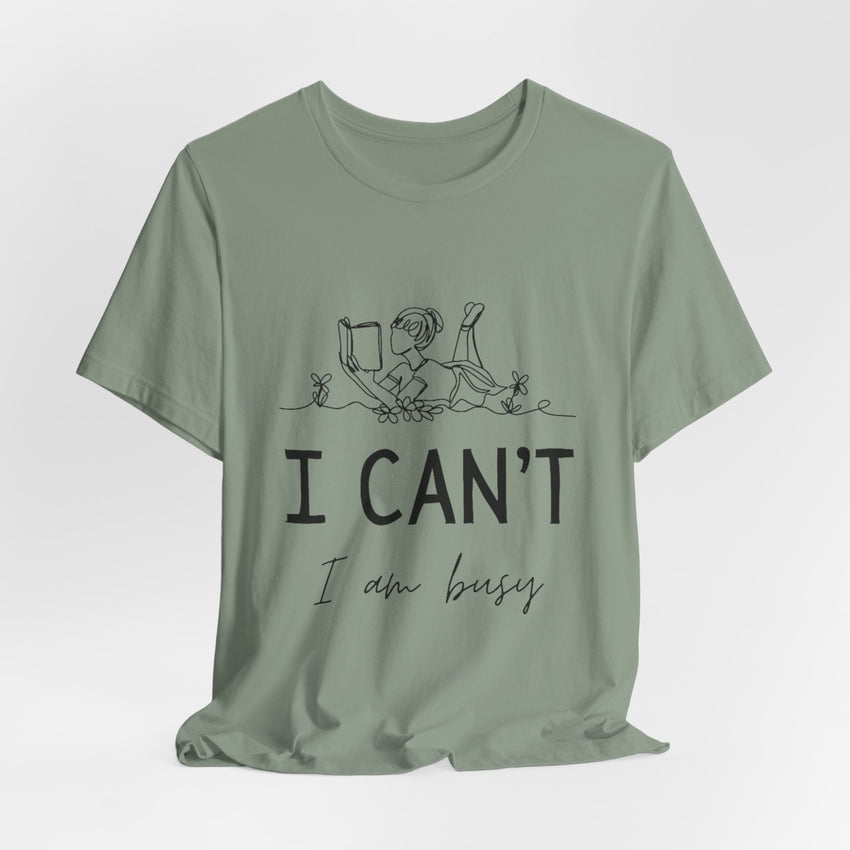 I Can’t, I’m Busy Unisex Jersey Short Sleeve TeeShow off your love for quiet moments with our I Can’t, I’m Busy Unisex Jersey Short Sleeve Tee. Perfect for book lovers and those who cherish their downtime, this tee features a playful illustration of a per