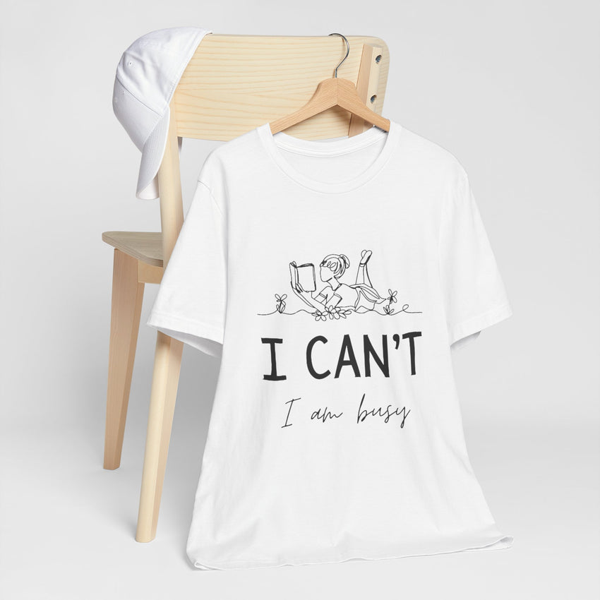 I Can’t, I’m Busy Unisex Jersey Short Sleeve TeeShow off your love for quiet moments with our I Can’t, I’m Busy Unisex Jersey Short Sleeve Tee. Perfect for book lovers and those who cherish their downtime, this tee features a playful illustration of a per