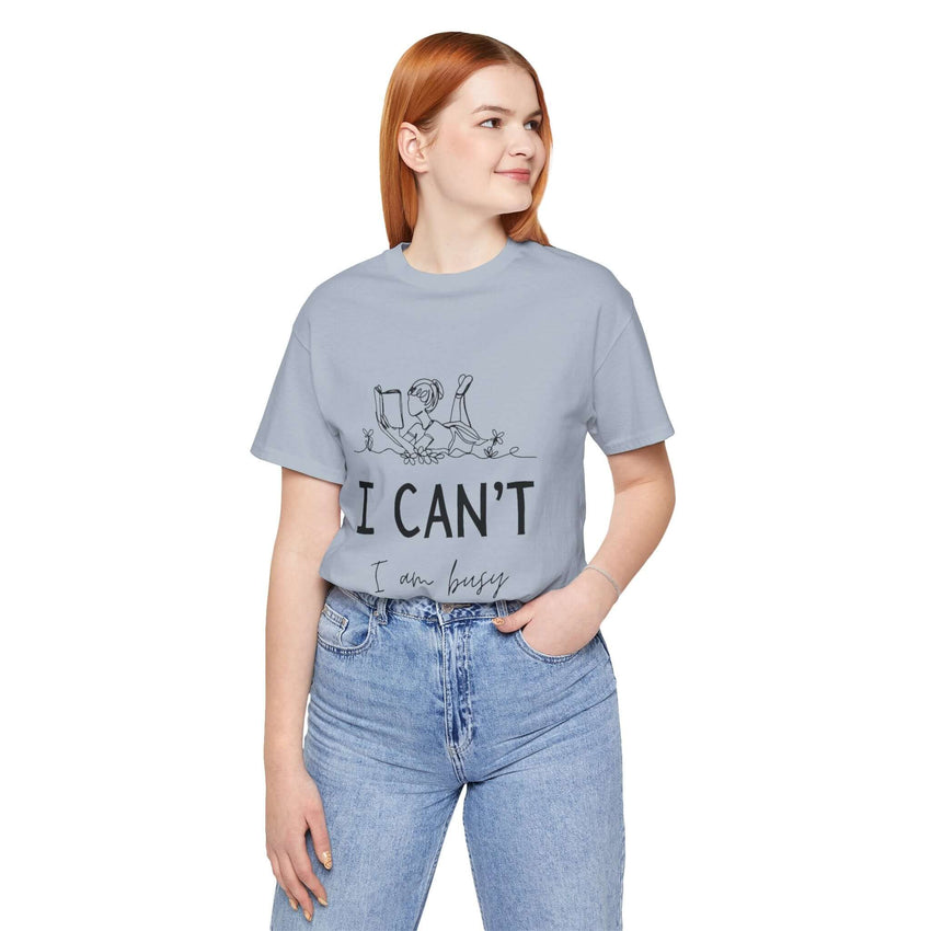 I Can’t, I’m Busy Unisex Jersey Short Sleeve TeeShow off your love for quiet moments with our I Can’t, I’m Busy Unisex Jersey Short Sleeve Tee. Perfect for book lovers and those who cherish their downtime, this tee features a playful illustration of a per