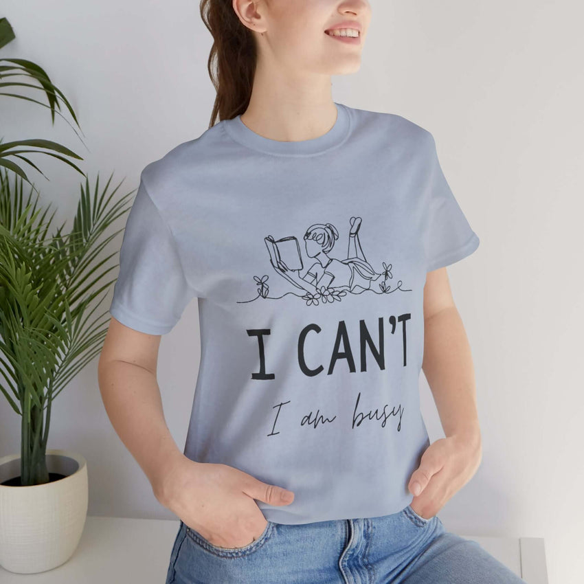 I Can’t, I’m Busy Unisex Jersey Short Sleeve TeeShow off your love for quiet moments with our I Can’t, I’m Busy Unisex Jersey Short Sleeve Tee. Perfect for book lovers and those who cherish their downtime, this tee features a playful illustration of a per