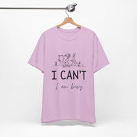 I Can’t, I’m Busy Unisex Jersey Short Sleeve TeeShow off your love for quiet moments with our I Can’t, I’m Busy Unisex Jersey Short Sleeve Tee. Perfect for book lovers and those who cherish their downtime, this tee features a playful illustration of a per