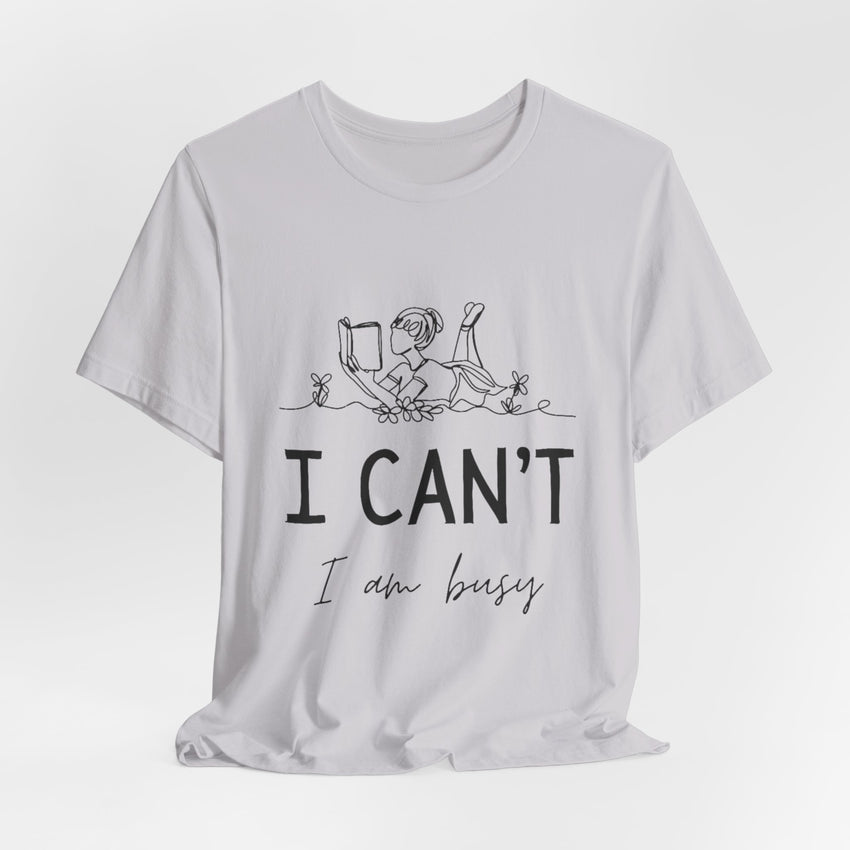 I Can’t, I’m Busy Unisex Jersey Short Sleeve TeeShow off your love for quiet moments with our I Can’t, I’m Busy Unisex Jersey Short Sleeve Tee. Perfect for book lovers and those who cherish their downtime, this tee features a playful illustration of a per