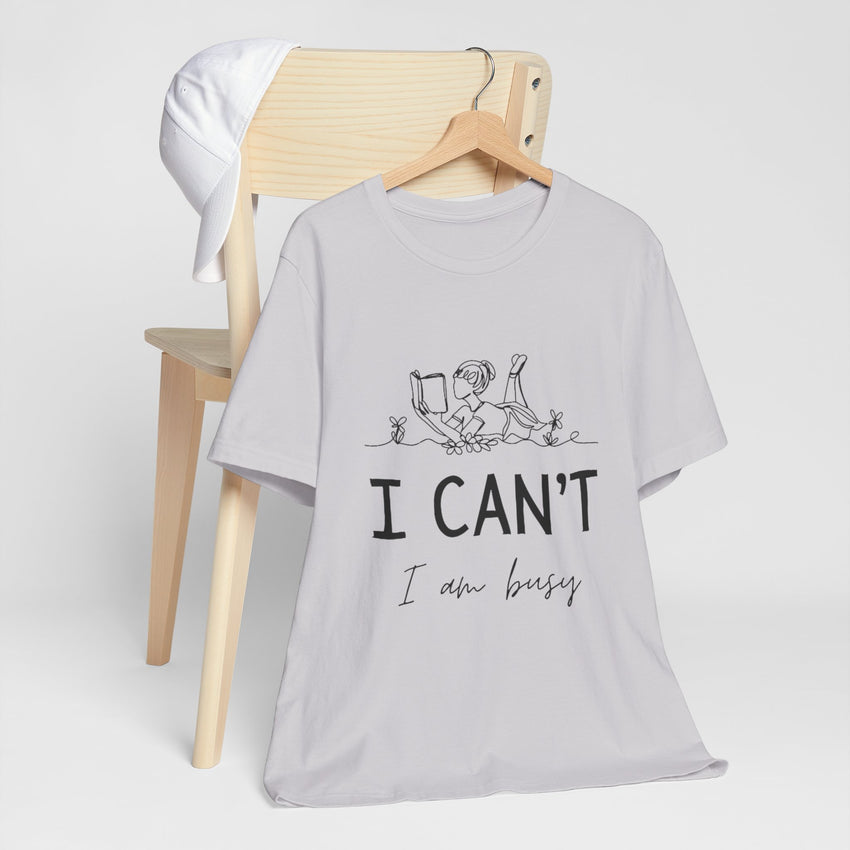 I Can’t, I’m Busy Unisex Jersey Short Sleeve TeeShow off your love for quiet moments with our I Can’t, I’m Busy Unisex Jersey Short Sleeve Tee. Perfect for book lovers and those who cherish their downtime, this tee features a playful illustration of a per