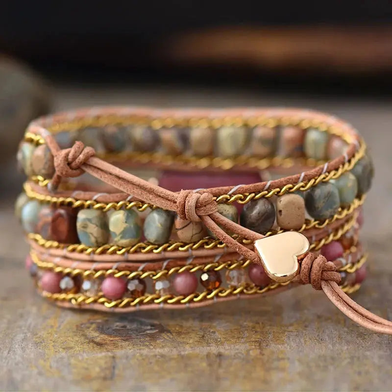 Rhodonite Heart Wrap Bracelet Experience the beauty of nature and fashion with our Rhodonite Heart Wrap Bracelet. This multi-layered, hand-woven bracelet showcases skilled craftsmanship and sophistication with natural stone and red wood grain beads. The r