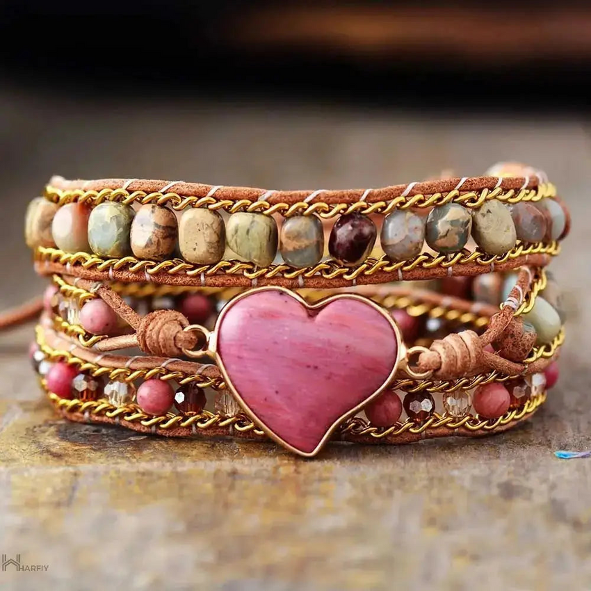 Rhodonite Heart Wrap Bracelet Experience the beauty of nature and fashion with our Rhodonite Heart Wrap Bracelet. This multi-layered, hand-woven bracelet showcases skilled craftsmanship and sophistication with natural stone and red wood grain beads. The r