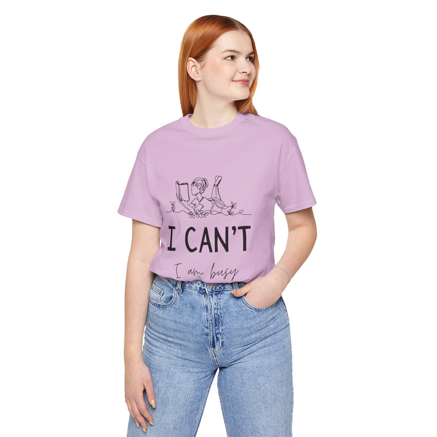 I Can’t, I’m Busy Unisex Jersey Short Sleeve TeeShow off your love for quiet moments with our I Can’t, I’m Busy Unisex Jersey Short Sleeve Tee. Perfect for book lovers and those who cherish their downtime, this tee features a playful illustration of a per