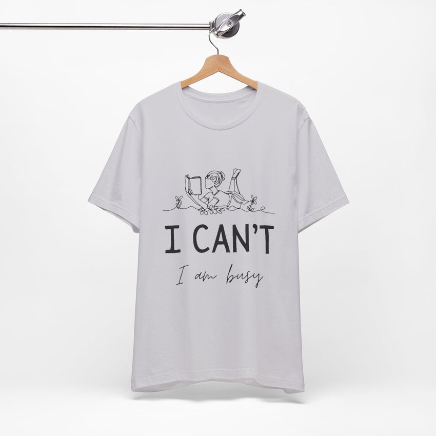 I Can’t, I’m Busy Unisex Jersey Short Sleeve TeeShow off your love for quiet moments with our I Can’t, I’m Busy Unisex Jersey Short Sleeve Tee. Perfect for book lovers and those who cherish their downtime, this tee features a playful illustration of a per