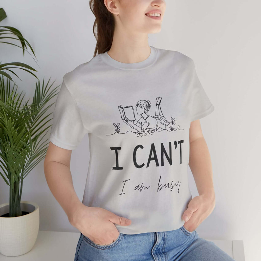 I Can’t, I’m Busy Unisex Jersey Short Sleeve TeeShow off your love for quiet moments with our I Can’t, I’m Busy Unisex Jersey Short Sleeve Tee. Perfect for book lovers and those who cherish their downtime, this tee features a playful illustration of a per